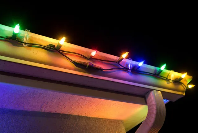 Colored lights clipped along a roof edge and gutter at night