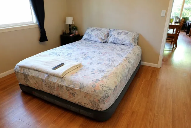 An inflated air mattress made up with a floral sheet in a bedroom